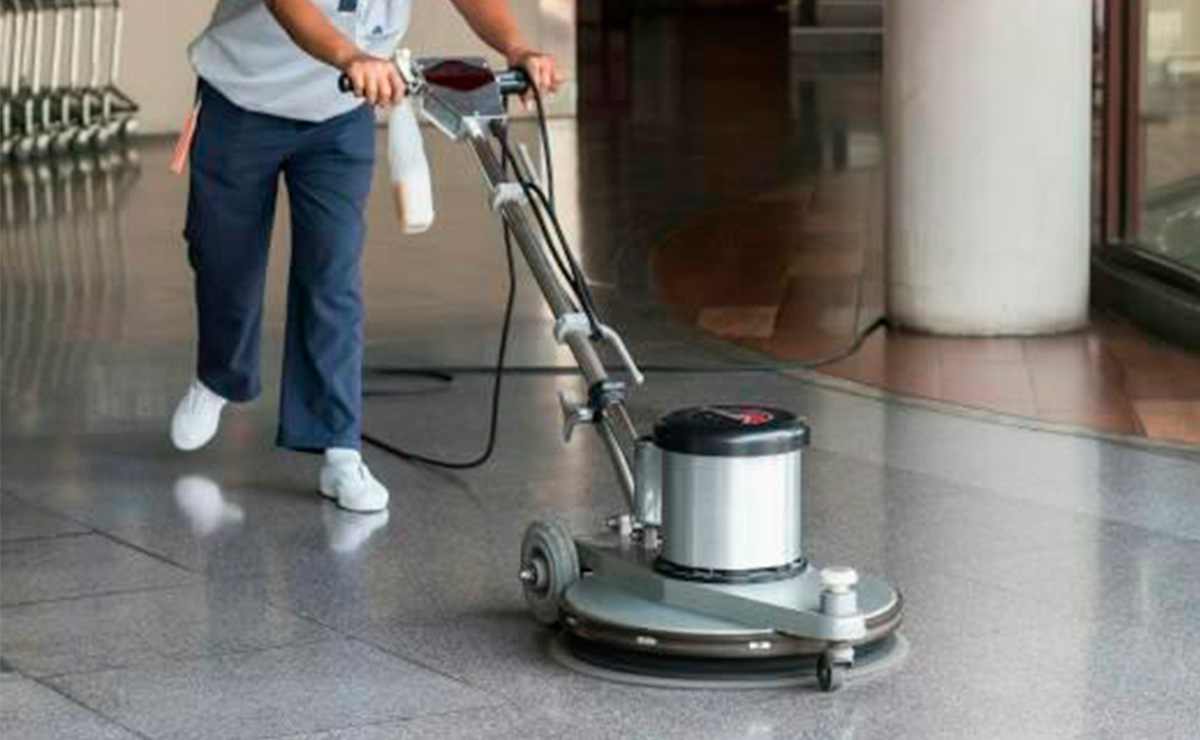 Máquina pulidora y personal de limpieza dando mantenimiento al piso